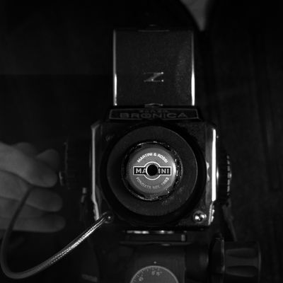 Bronica S2a, sporting a box camera lens with a Martini bottle cap aperture, taking this photo of itself; or how to make a medium format hobo lens for <$10
